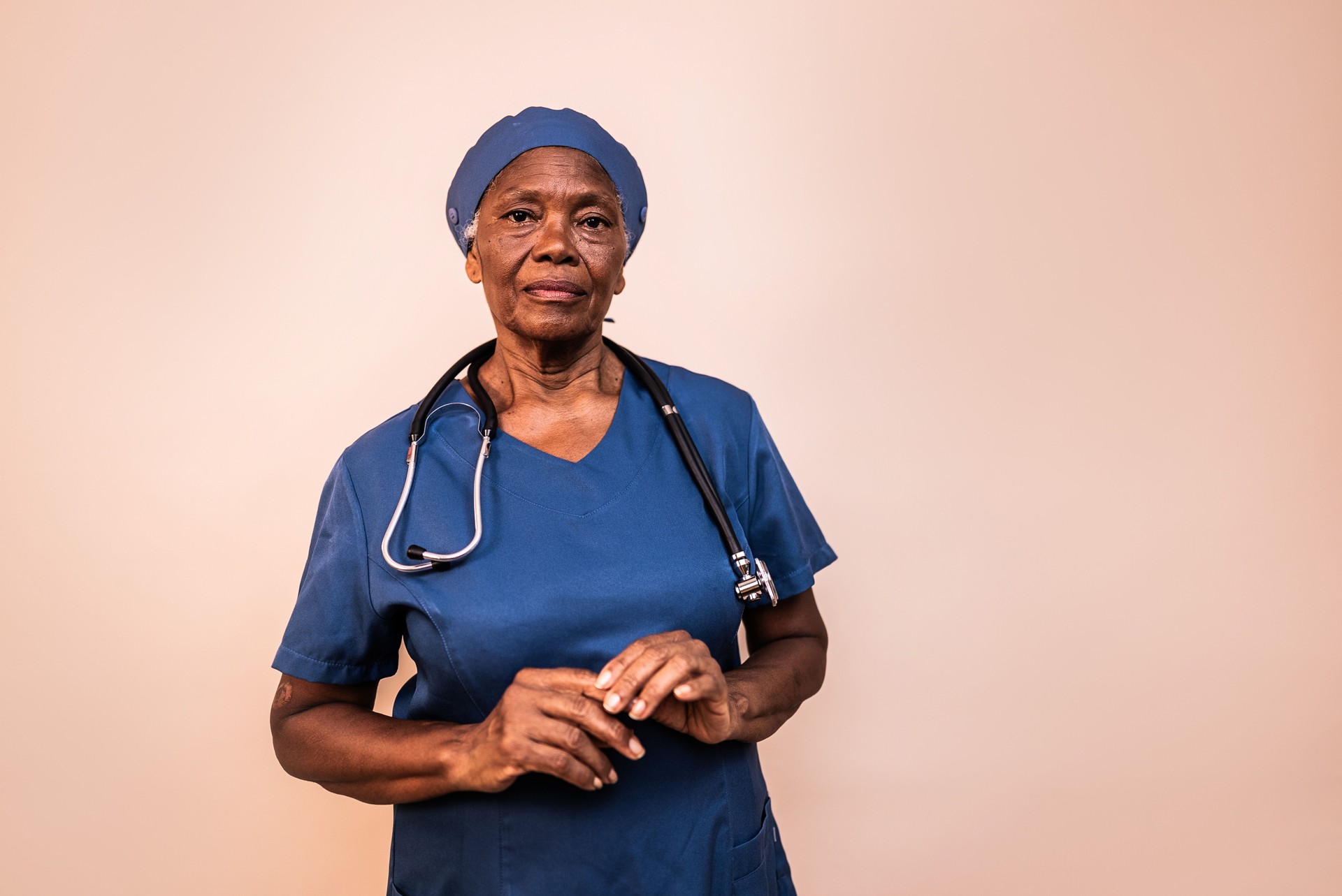 Portrait of senior nurse woman on a studio shot with cream colored background